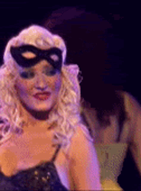 a woman is wearing a mask on her face and dancing on a stage .