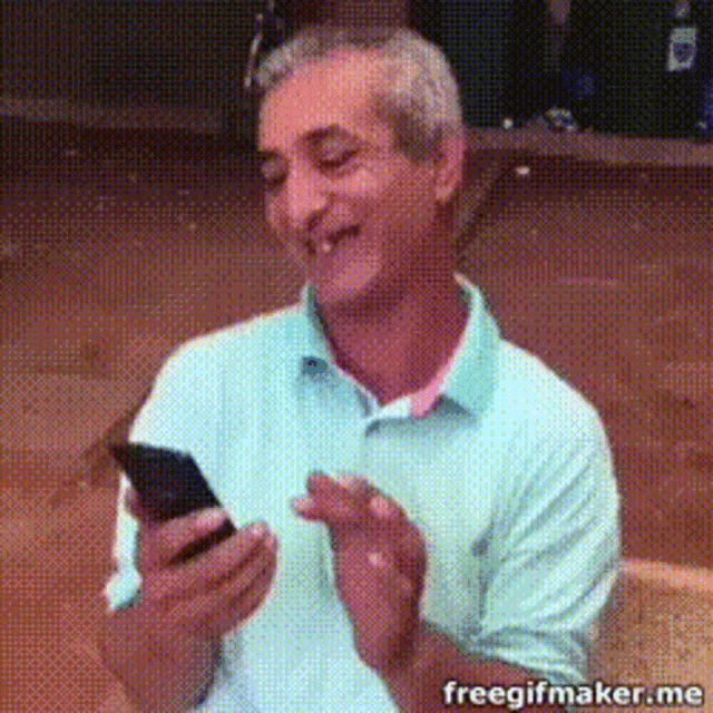 a man is smiling while looking at a cell phone with the words freegifmaker.me written below him