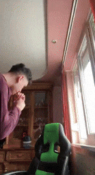 a young man is praying in front of a window in a living room .