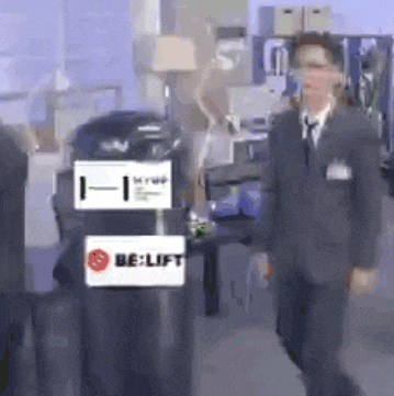 a man in a suit and tie is walking past a be lift sign