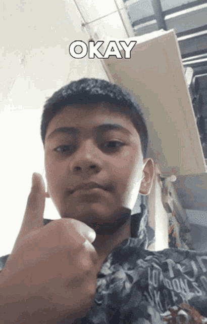 a young boy is giving a thumbs up with the word okay above his head