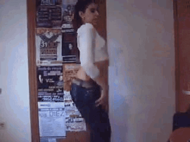 a woman is standing in front of a wall with posters on it including one that says rock