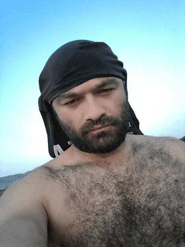 a man with a beard and a bandana on his head looks at the camera