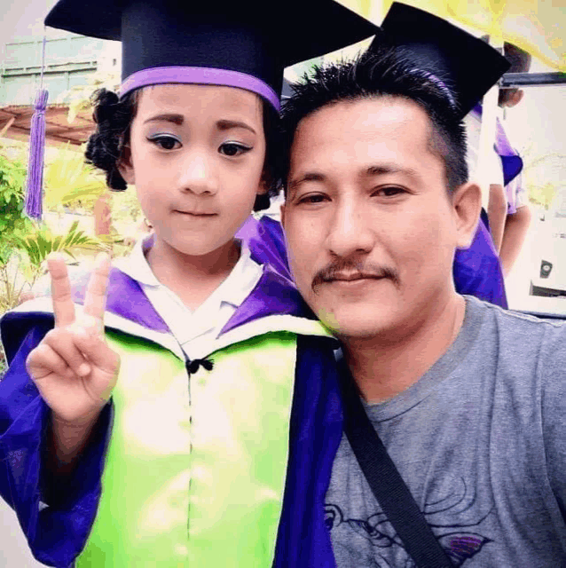 a little girl in a graduation cap and gown poses for a picture with her father