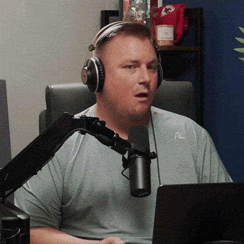 a man wearing headphones talks into a microphone in front of a laptop computer