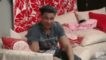 a man wearing a beret is sitting on a couch in a living room