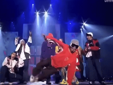 a group of men are dancing on a stage in front of a crowd .