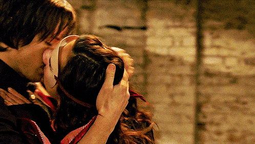 a man is kissing a woman who is wearing a mask on her face .
