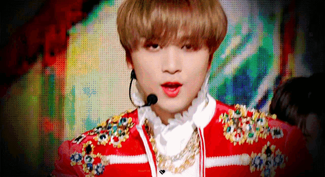 a young man wearing a red and white striped jacket and a microphone