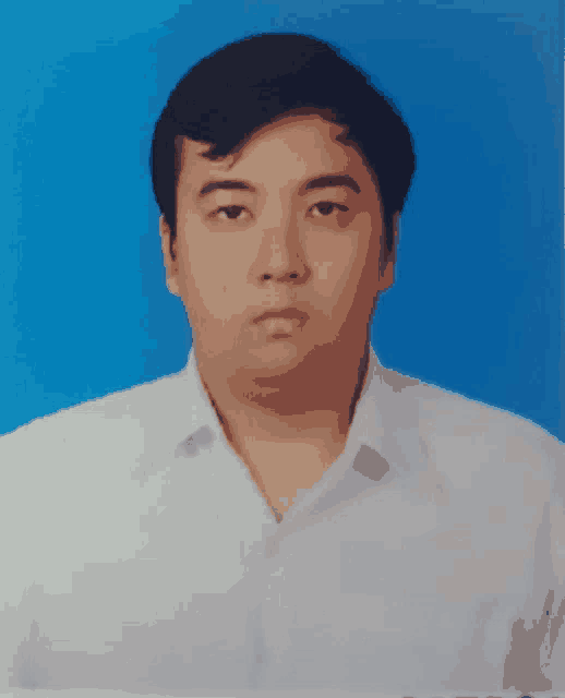 a man in a white shirt stands in front of a blue backdrop