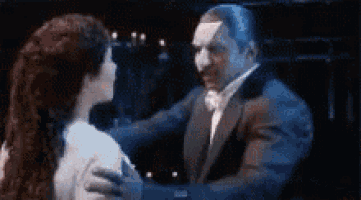a man in a tuxedo is dancing with a woman in a white dress on a stage .