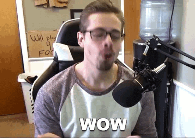a man sitting in front of a microphone with the word wow written on his chest