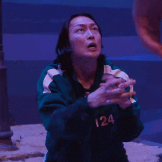 a woman in a green jacket is praying with her hands folded in front of her face