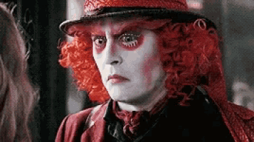 a close up of a person wearing a red wig and hat .