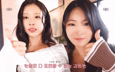 two girls are giving each other a thumbs up in a room