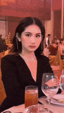 a woman is sitting at a table with a glass of wine in front of her .