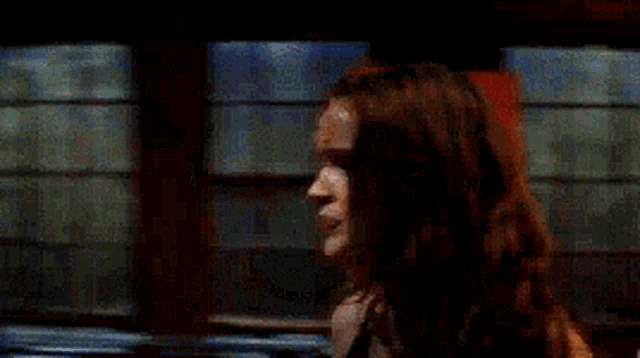 a woman with long red hair is standing in a dark room .