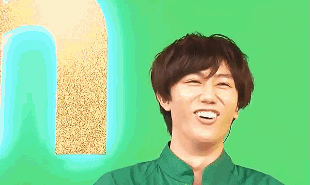 a man is smiling in front of a green background