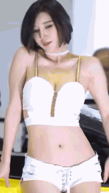 a woman in a white top and white shorts is dancing on a stage .
