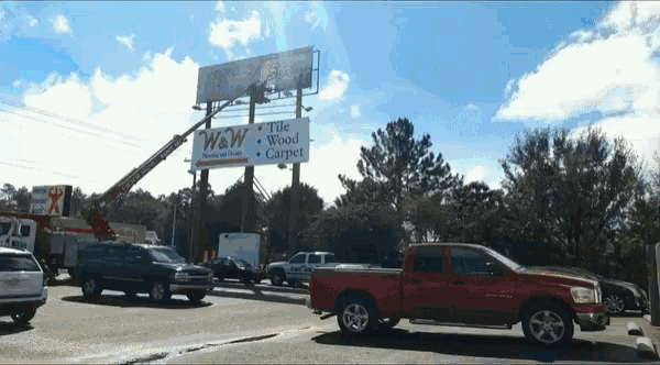 a red truck is parked in front of a billboard for w & w flooring and supplies