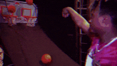 a man in a red shirt is standing in front of a basketball hoop and looking at the camera .