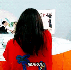 a woman in a red sweater says marc on the back of her shirt