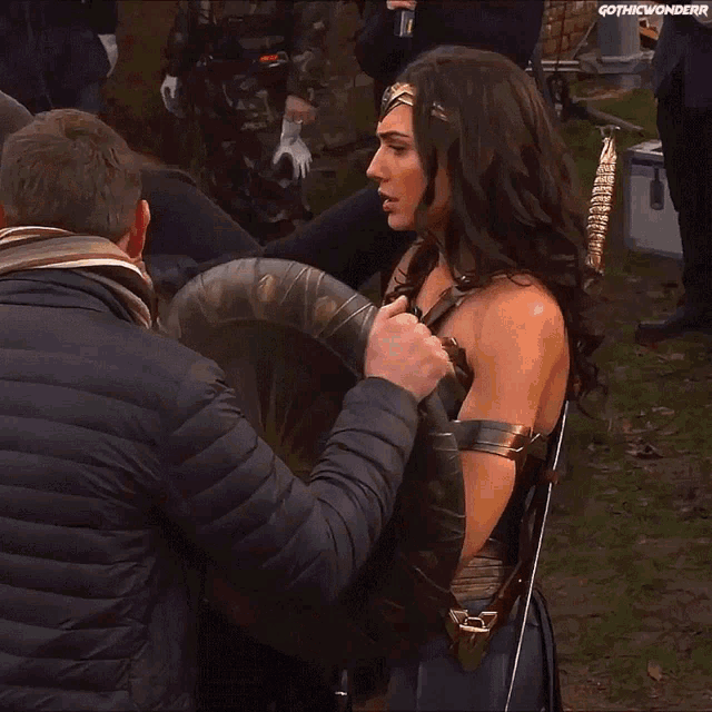 a woman in a wonder woman costume is holding a large shield
