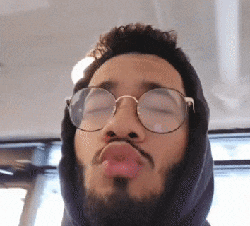 a man wearing glasses and a hoodie is making a face