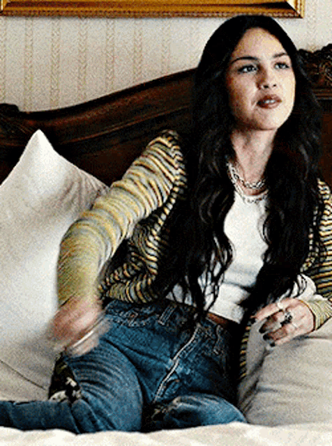 a woman with long hair is sitting on a bed