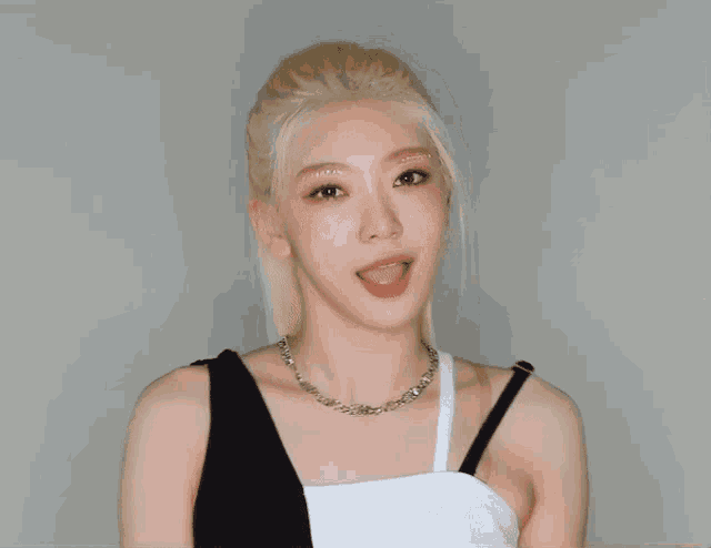 a woman with blonde hair is wearing a black and white top and a silver necklace