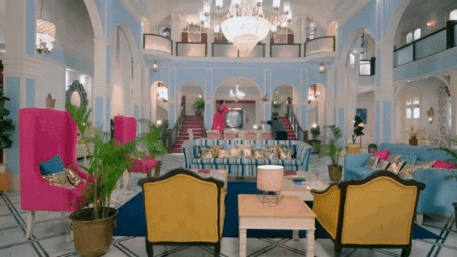a woman in a pink dress is standing in a living room with lots of furniture