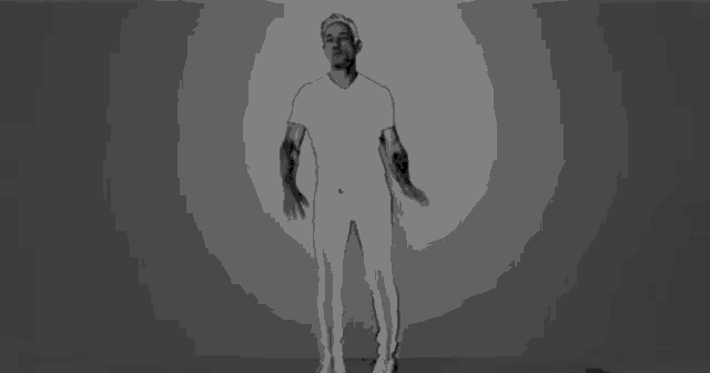 a man in white pants and a white shirt is dancing in a black and white photo .