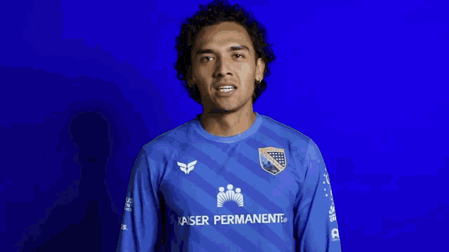 a man wearing a blue kaiser permanente jersey looks at the camera