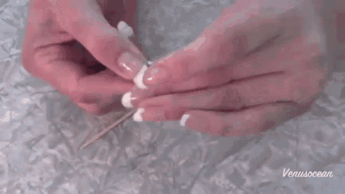 a close up of a woman 's hand holding a rose with a toothpick and the words venusocean visible