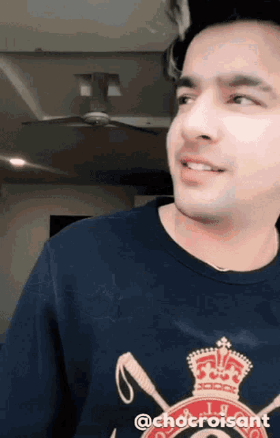 a man wearing a polo shirt with a crown and swords on it