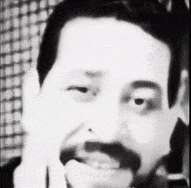 a black and white photo of a man with a beard making a face .