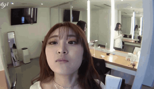 a woman is making a face in front of a mirror with the letters lyjl on the bottom