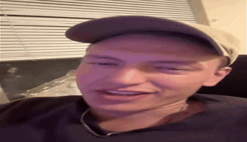 a man wearing a hat and a necklace is smiling .