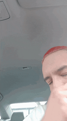 a man with red eyes is sitting in the driver 's seat of his car