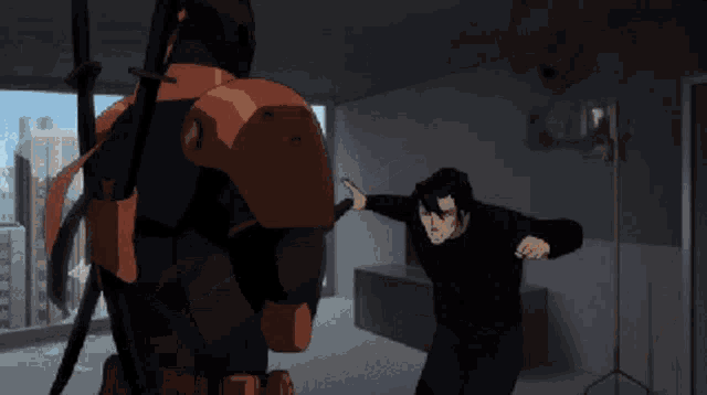 a man in a black shirt is being punched by a man in a red suit
