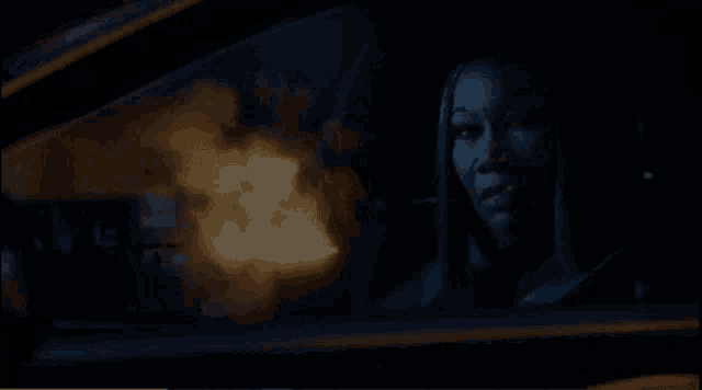 a woman is driving a car at night and looking out the window at a fire