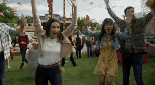 a group of people are dancing in a field with their arms in the air