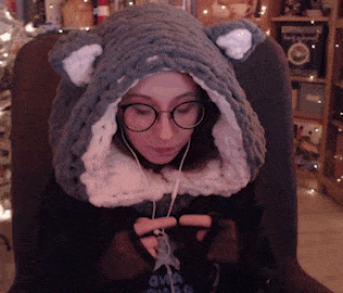 a woman wearing glasses and a knitted hat with ears is sitting in a chair