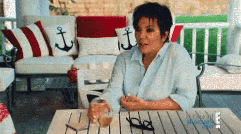 a woman is sitting at a table with a glass of wine in her hand .