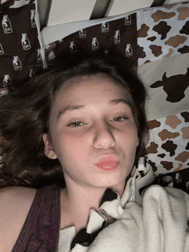 a girl is laying on a bed with a cow print pillow