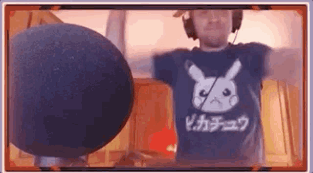 a man in a pikachu t-shirt is standing in front of a microphone .