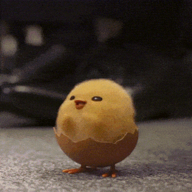 a small yellow chick in an egg shell walking on the ground