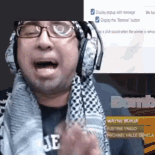 a man wearing headphones and a scarf around his neck is talking on a video call