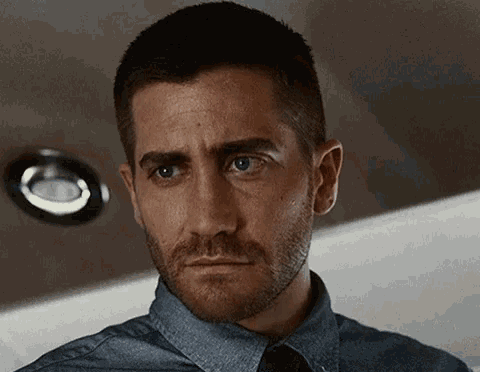 a man with a beard and blue eyes is wearing a denim shirt and tie