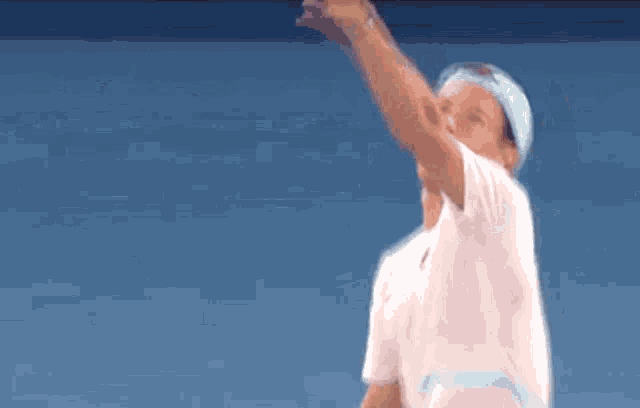 a tennis player wearing a headband and a white shirt is serving a ball